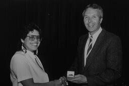 Principal Barry Moore presents to unidentified student at award ceremony.