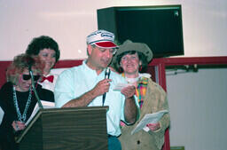 Rae McCombs at the mic at Frank Dolman's retirement party. In background are (left to right) Cheryl Isaac, Catherine Sorensen, and Catherine McDonald. All Continuing Education employees. Rae passed away in 2019.